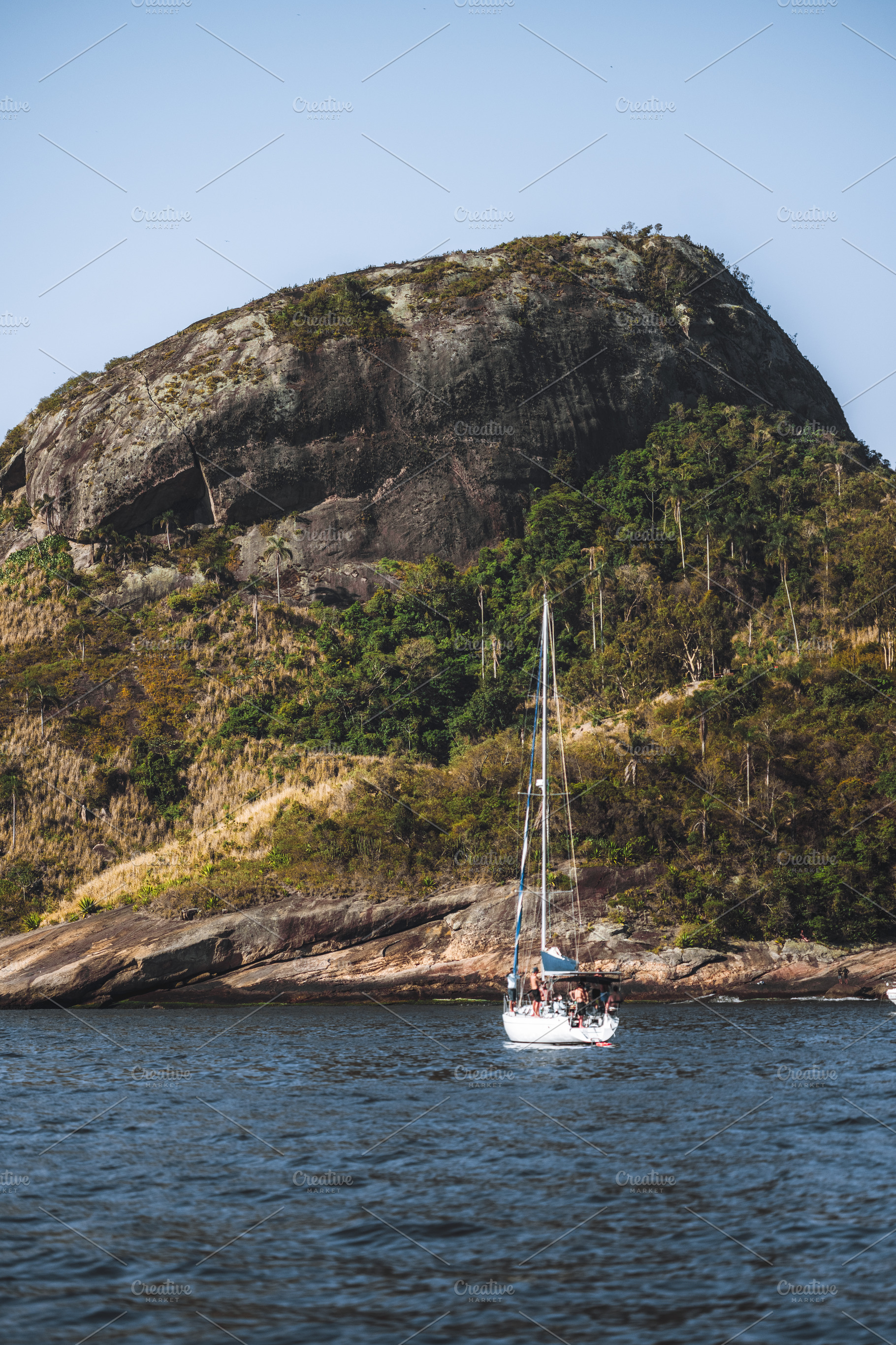 Rocky island behind blurred sailboat, a Sports & Recreation Photo by SkyNext