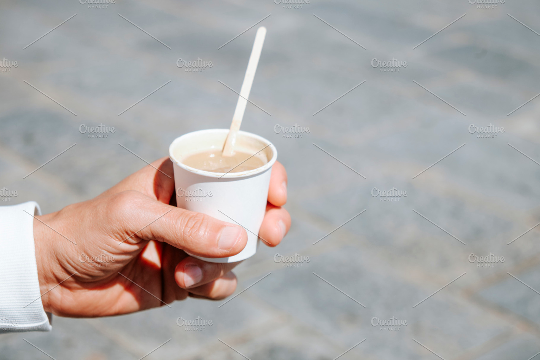 close-up of a man holding a takeaway cortado, a Photo by Nito