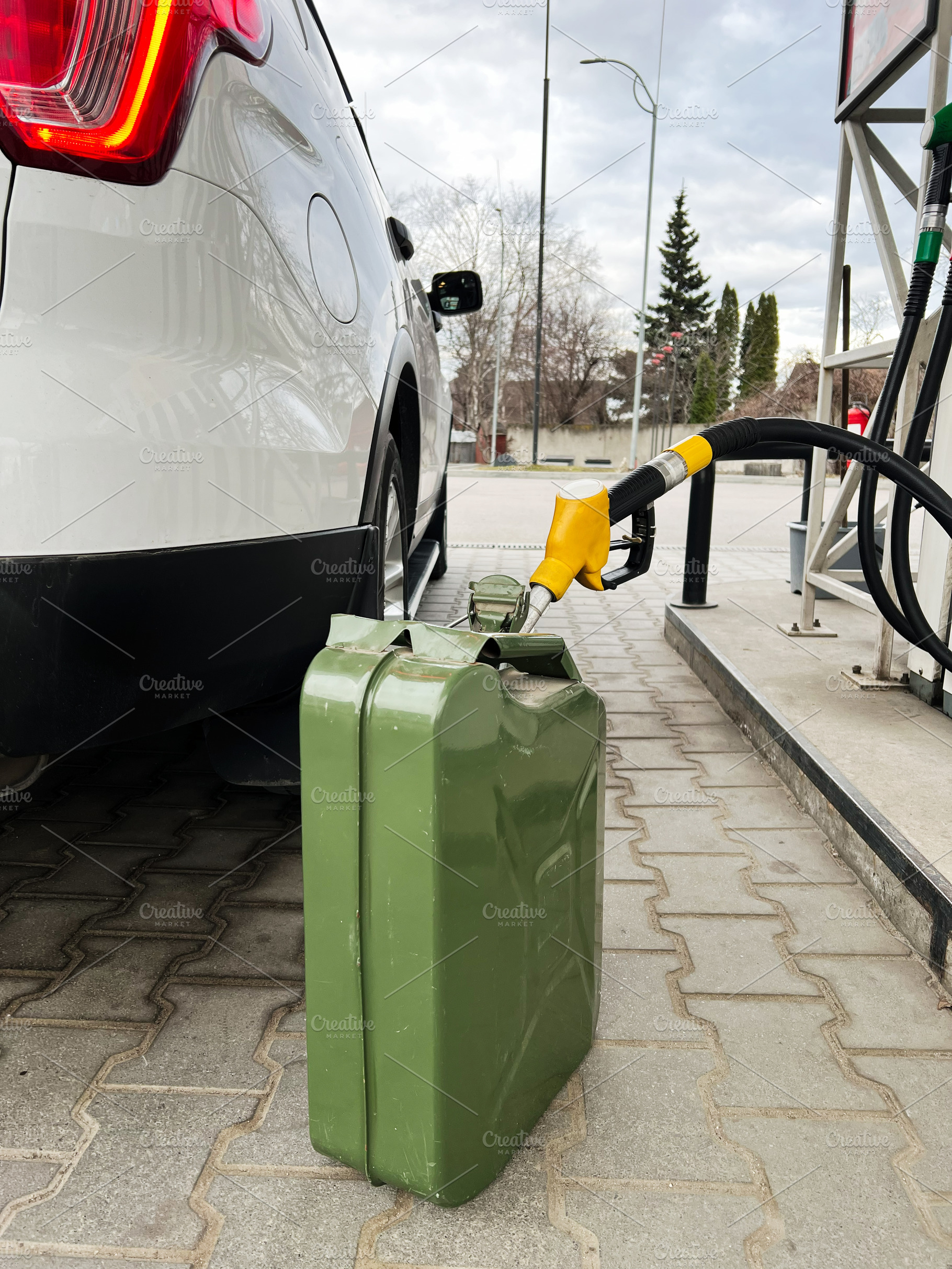 Green metal container and car fueling at a gas station under cloudy skies, a Photo by AS photostudio