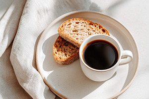Morning coffee and toasted bread served on a plate in warm sunlight setting, a Food & Drink Photo by AlyaAnd