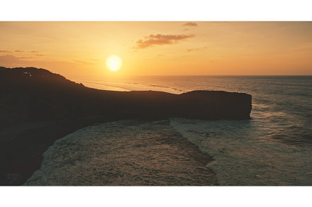 Sunset with rock silhouette at ocean, a Nature Photo by Goinyk