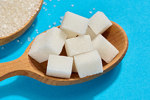 Wooden spoon filled with pieces of white refined sugar, blue bac, a Food & Drink Photo by ndanko