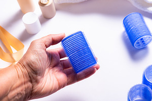 Female Hand Holding Blue Plastic Hair Roller with Hair Care Prod, a Business Photo by MDBildes