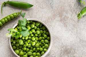 Fresh green peas in bowl and pods on rustic surface, a Food & Drink Photo by Olena Rudo