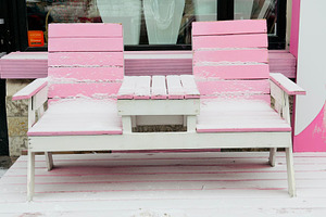 A pink and white outdoor bench covered in snow, situated in front of a shop win, an Industrial Photo by Textures & Backgrounds