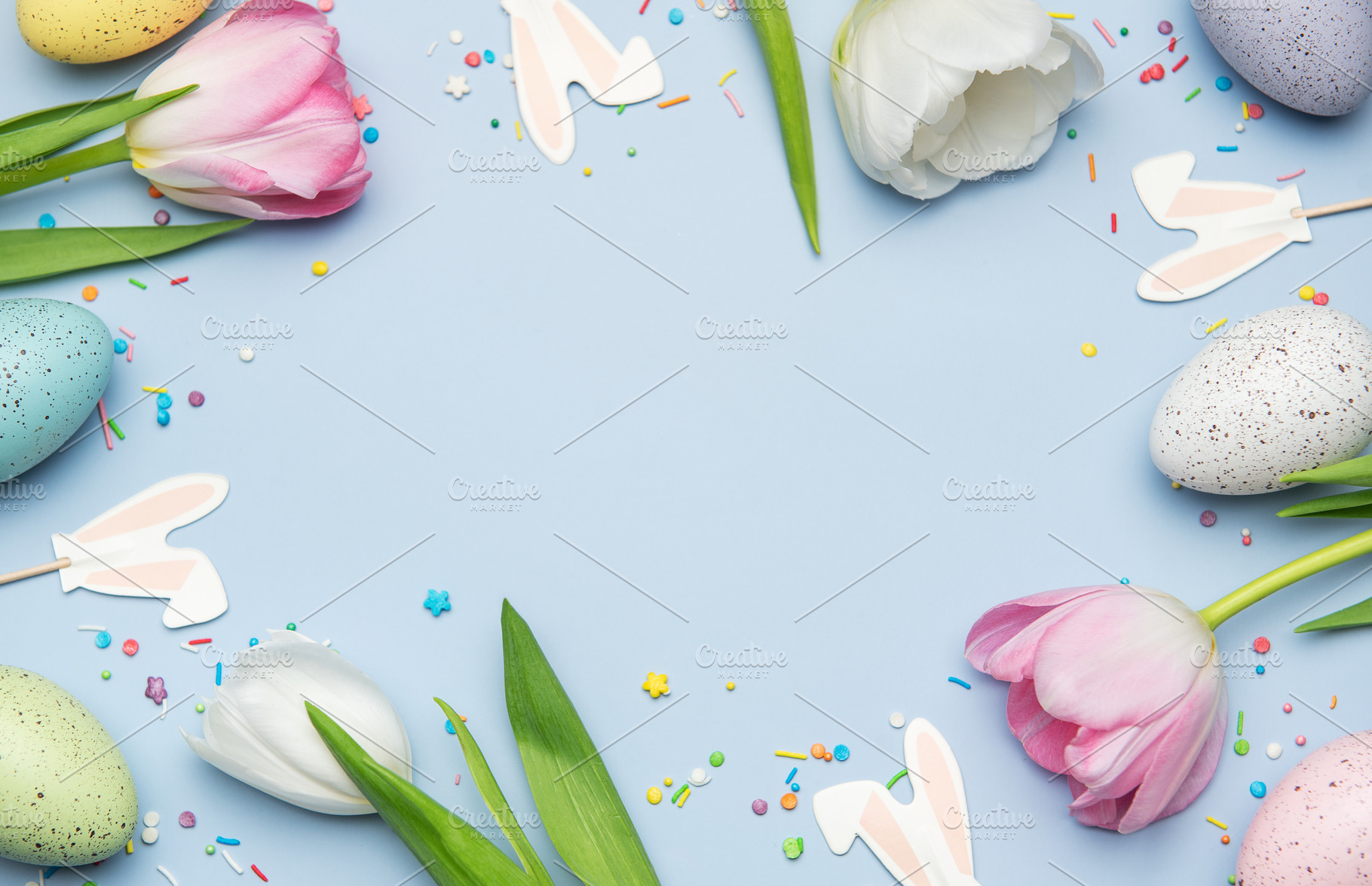 Easter eggs and tulips creating a frame on light blue background, a Photo by Olena Rudo