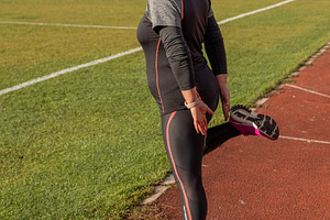 Woman stretching quad on track, a Photo by Grafvision photography