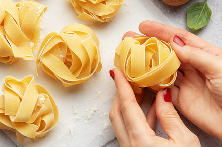 Chef preparing homemade tagliatelle pasta with eggs and basil, a Food & Drink Photo by Olena Rudo