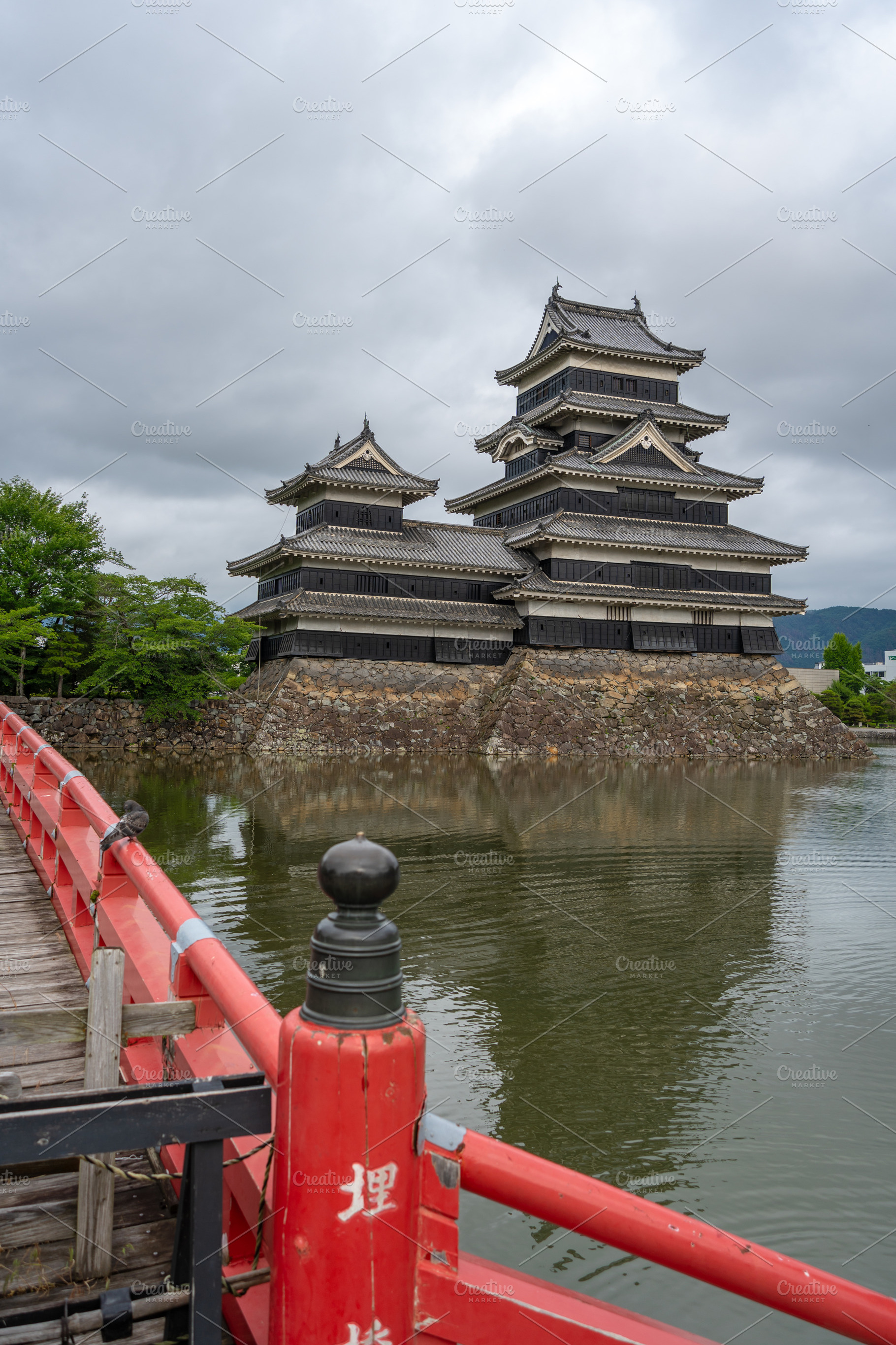 Red bridge leading to majestic Matsumoto Castle in Japan, an Architecture Photo by GoodGoods