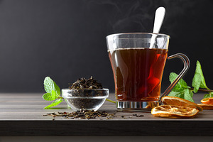 Black tea with orange and mint on a wooden table, isolated on bl, a Food & Drink Photo by Davizro's Market