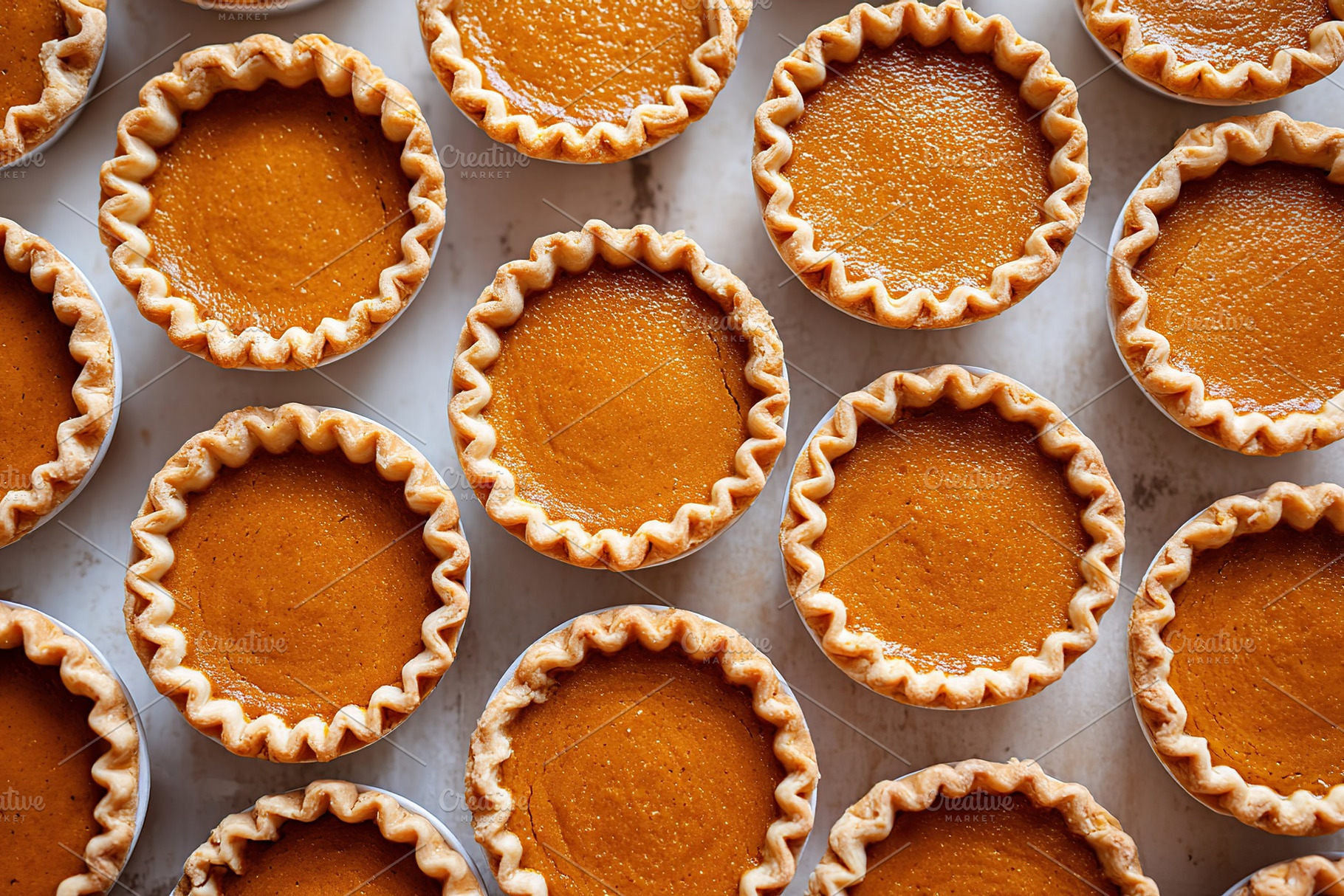 Mini pumpkin pie cups arranged neatly on a baking tray with golden crusts and s, a Food & Drink Photo by AlyaAnd