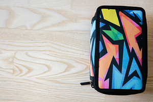 Colorful geometric zippered case on a wooden surface, a Photo by AS photostudio