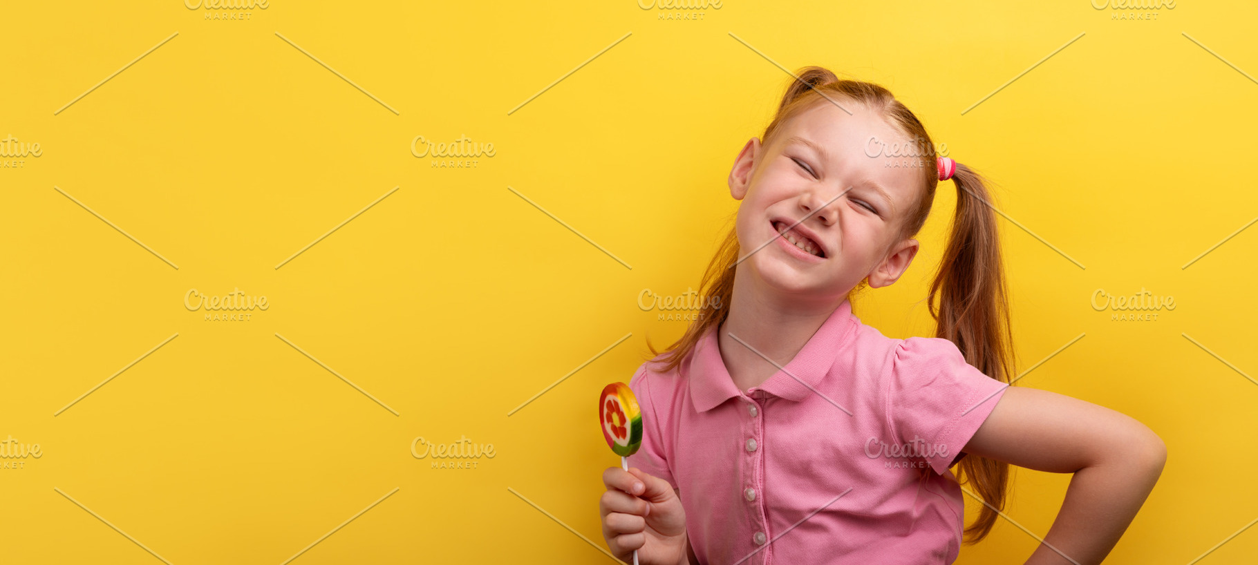 Cheerful young girl in pink shirt holding a colorful lollipop an, a Person Photo by Ales Munt