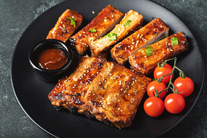 Hot grilled spare ribs from a summer BBQ served on a plate with sauce. Top view, a Food & Drink Photo by Budarinphoto