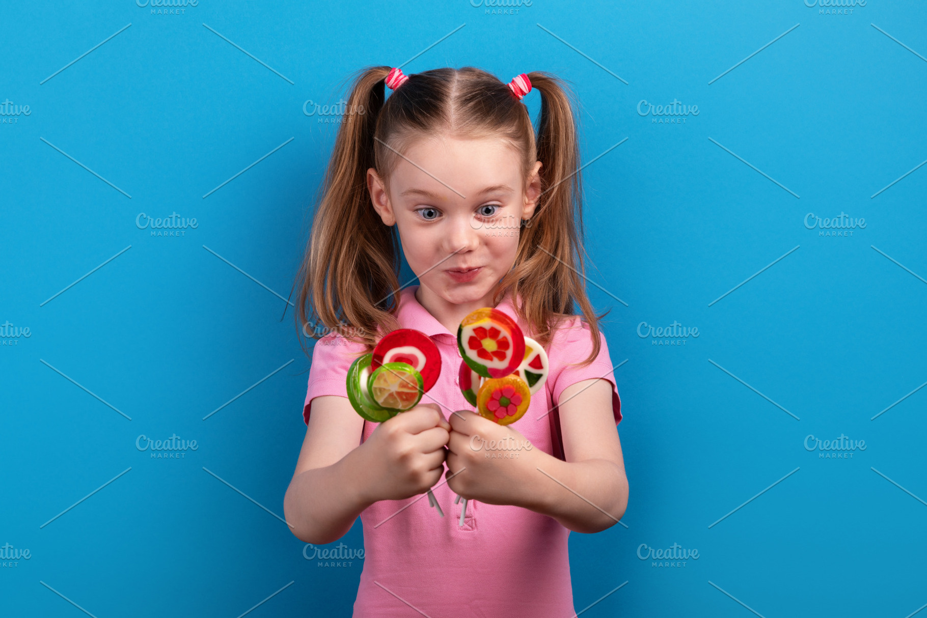 Surprised and excited young girl in a pink shirt holding colorfu, a Person Photo by Ales Munt