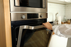Young woman hand open modern oven in kitchen, an Architecture Photo by AtlasStudio PRO