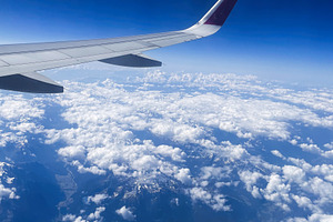 Airplane wing over stunning alpine mountains and fluffy clouds on a sunny day, a Photo by AS photostudio