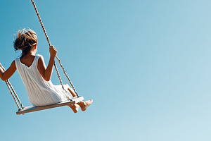 Young girl swings under a clear blue, a Person Photo by MistyDay