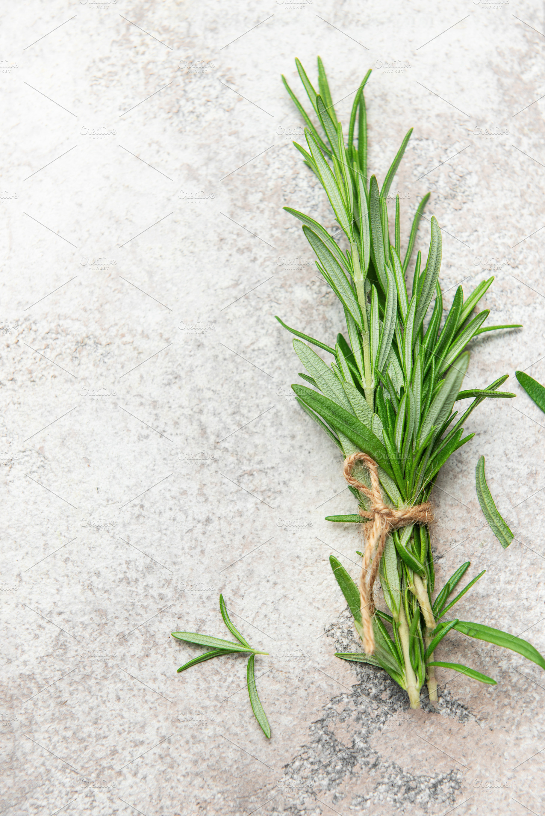 Fresh rosemary sprigs tied with twine on stone surface, a Food & Drink Photo by Olena Rudo