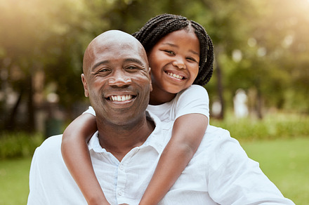Portrait of dad, girl in nature park and bonding together with a happy smile, piggyback hug and love. Black man, smiling child outdoors and relax on grass in summer sun on childhood holiday wellness, a Photo by Peopleimages.com
