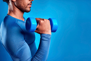 Half body sporty man lifting a dumbbell with blue background, a Sports & Recreation Photo by Davizro's Market