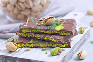Delicious milk chocolate bar with pistachio and kadaifi filing, lying on cuttin, a Food & Drink Photo by iuliia_n