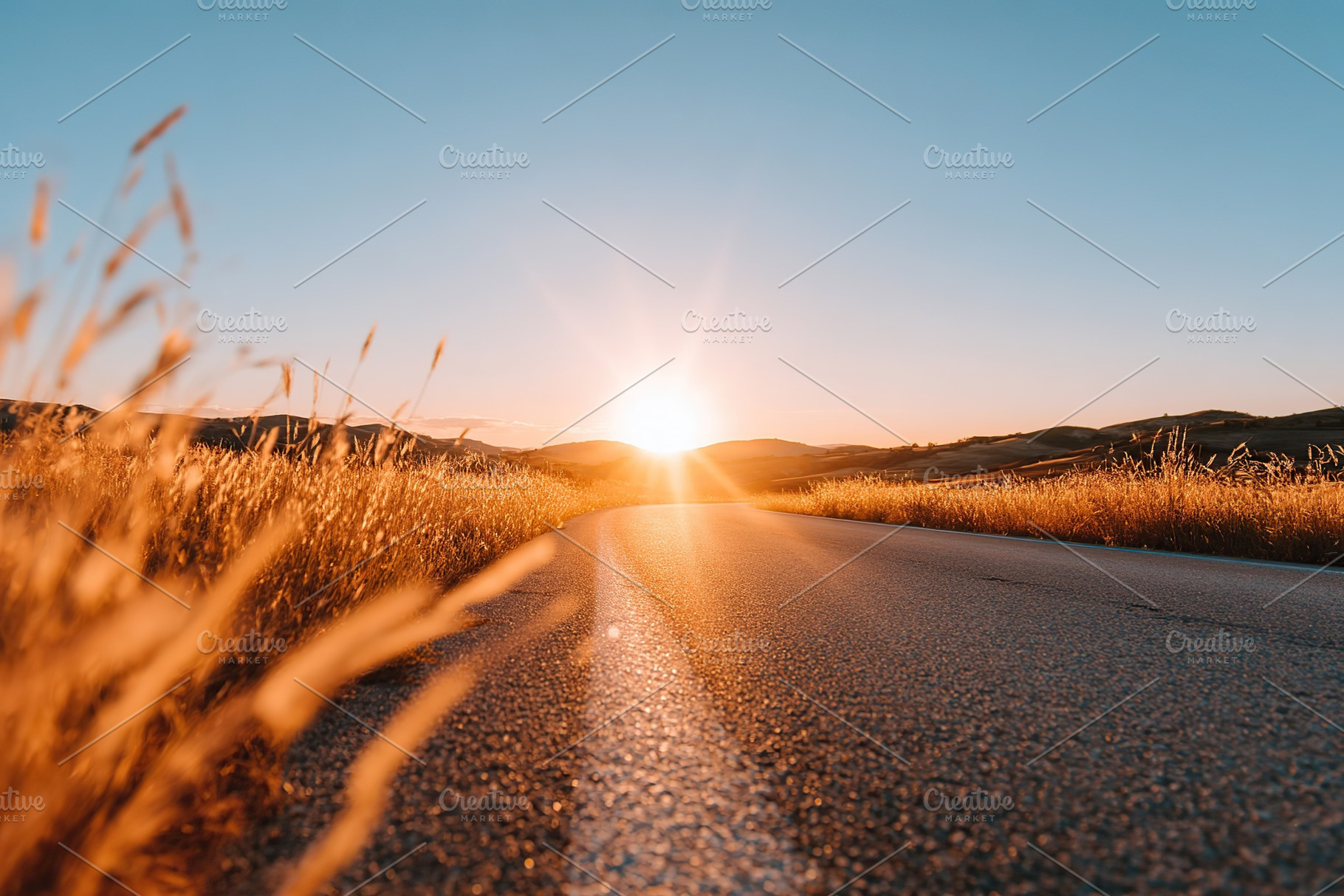 Scenic countryside road stretches before the sunset over rolling hills and gold, a Photo by AlyaAnd