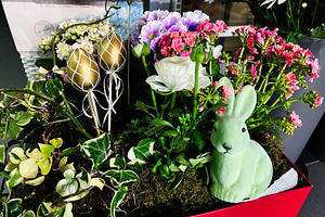 Decorative Easter arrangement with flowers, golden eggs, and a green bunny figu, a Photo by AS photostudio