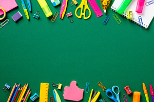 Back to school concept. Creative layout with colorful school supplies on green