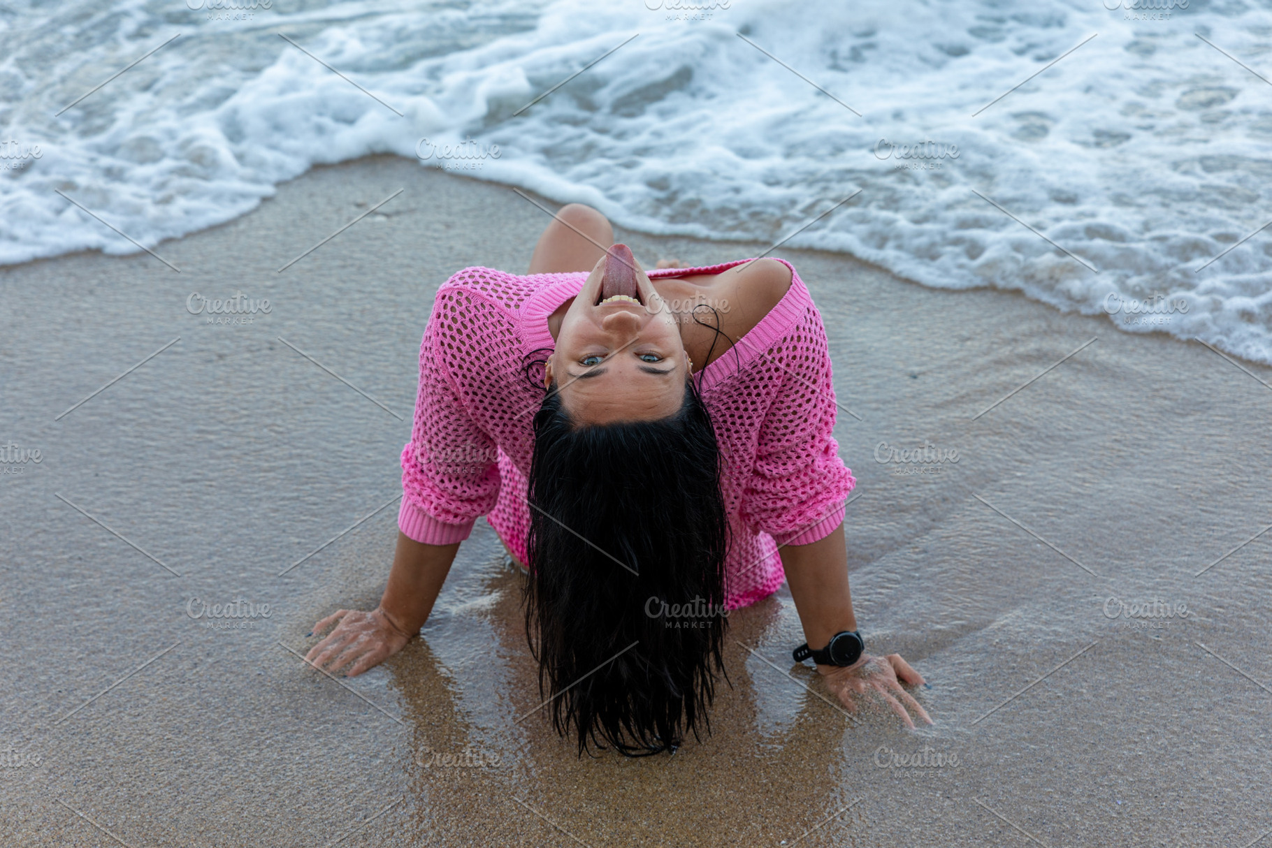 Smiling woman in pink sweater enjoys the beach, leaning back on wet sand with o, a Person Photo by Ales Munt
