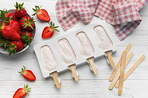 Strawberry popsicles in making process on white wooden surface, a Food & Drink Photo by Olena Rudo