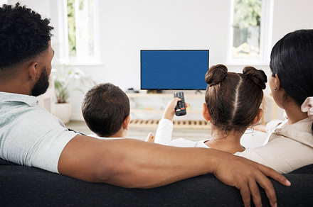 Tv watching family, relaxed and enjoying entertainment streaming movies, series or shows at home back view. Parents and kids spending leisure time, looking at cartoons or youth television copyspace, a Photo by Peopleimages.com