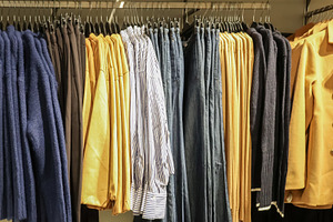 Clothing selection hanging on display racks in a retail store, showing various, a Photo by Studio ANNA