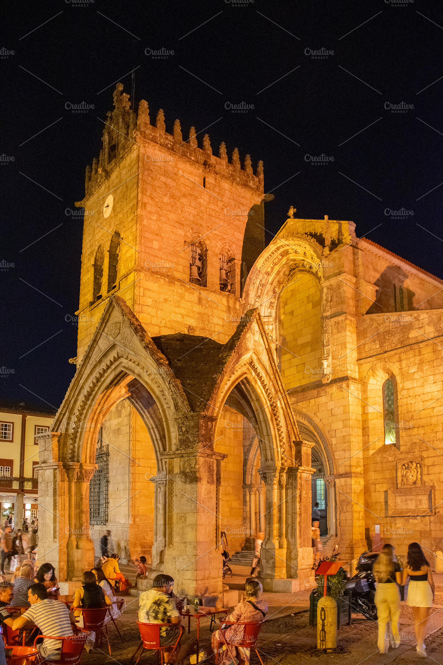 Historic stone chapel with outdoor café at night, guimaraes, po, a Person Photo by DanFLCreativo