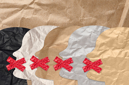 Cutout figures of heads with taped mouths on brown crumpled pape, an Abstract Photo by ndanko