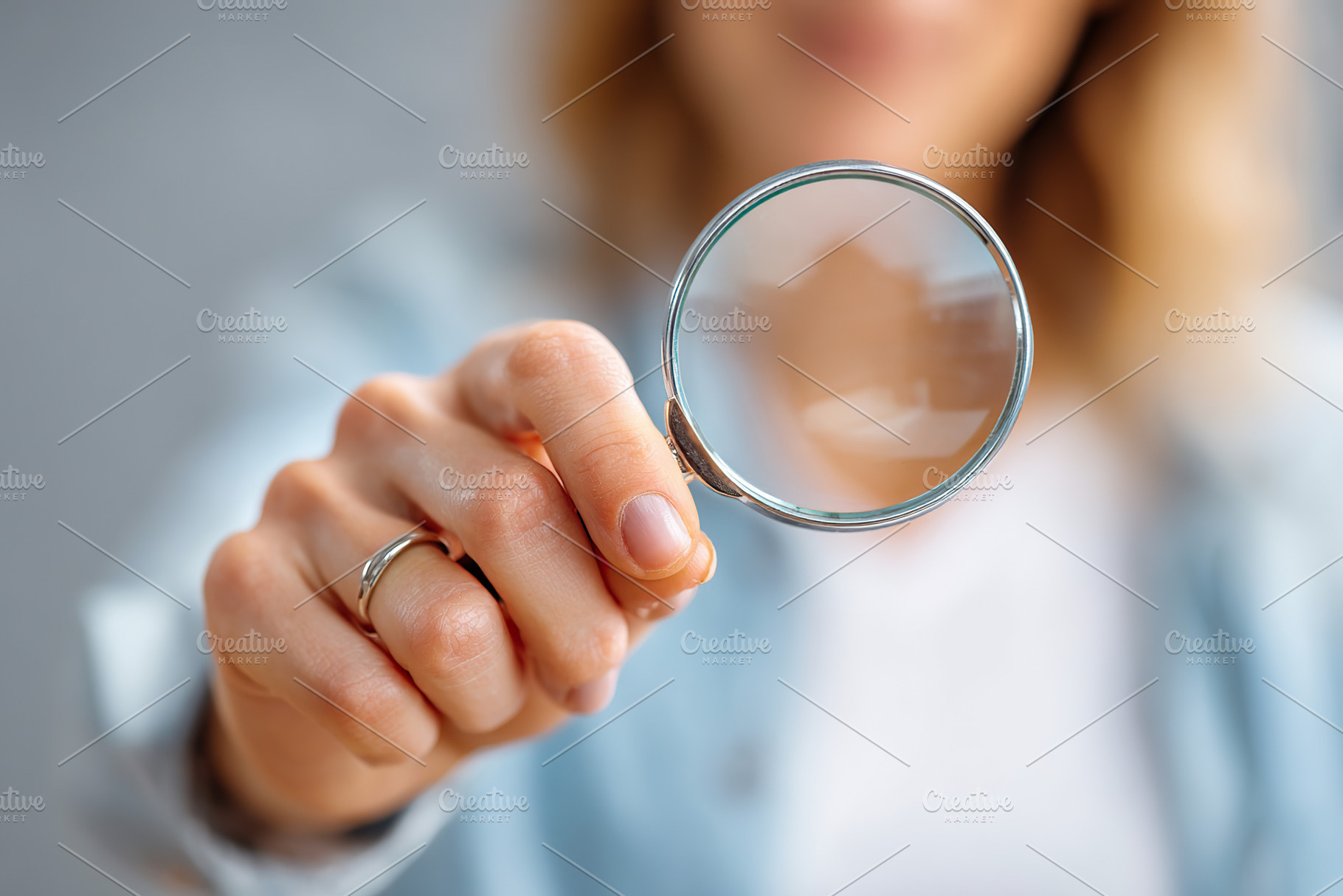 Straight female hand holding a magnifying glass against a blurred background in, a Photo by AlyaAnd