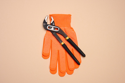 Orange glove and metal universal adjustable wrench on a beige ba, an Abstract Photo by ndanko