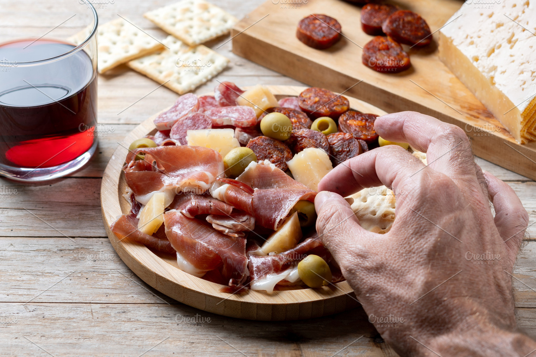 Hand picking up serrano ham from Spanish charcuterie board, a Food & Drink Photo by etorres69