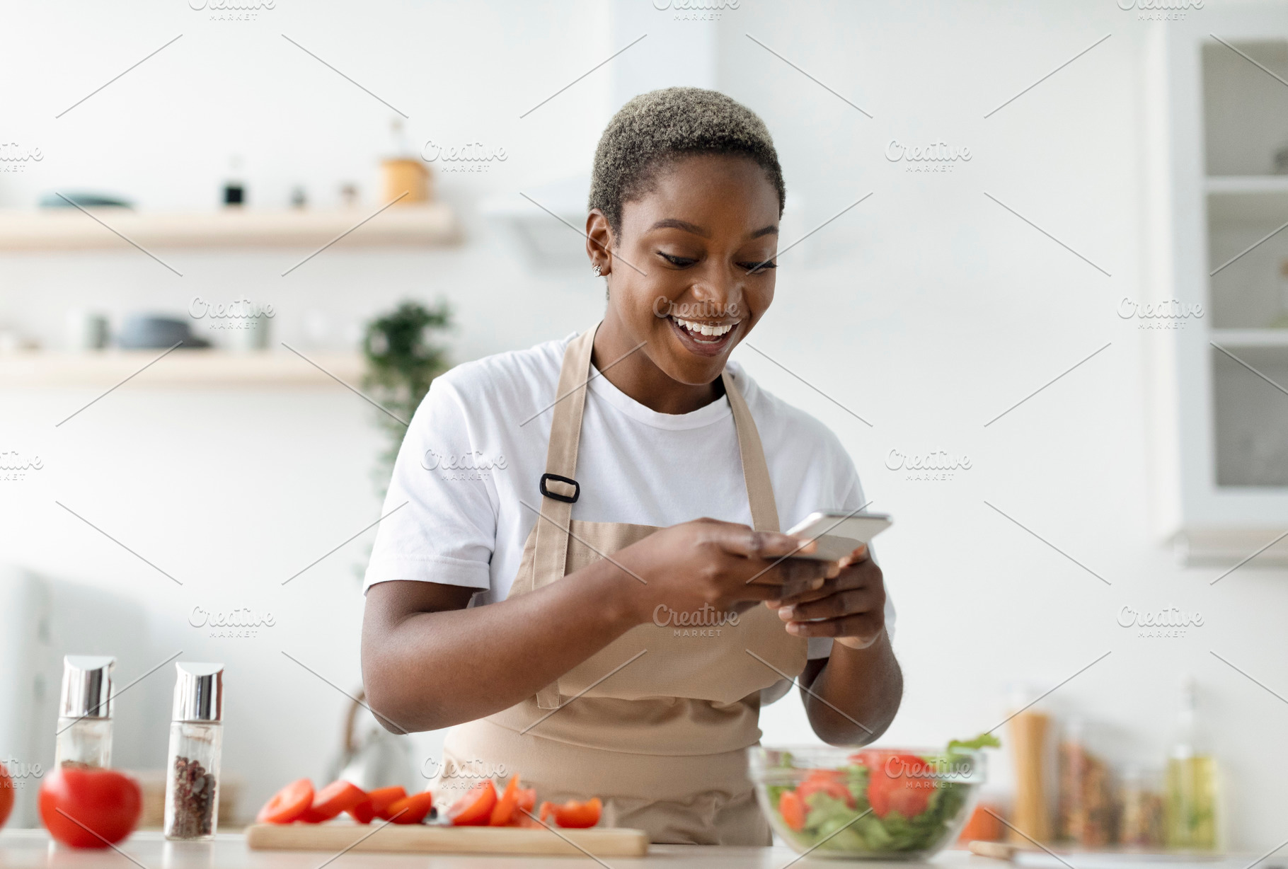 Smiling young pretty african american woman blogger in apron making photo of sa, a Person Photo by Prostock-Studio