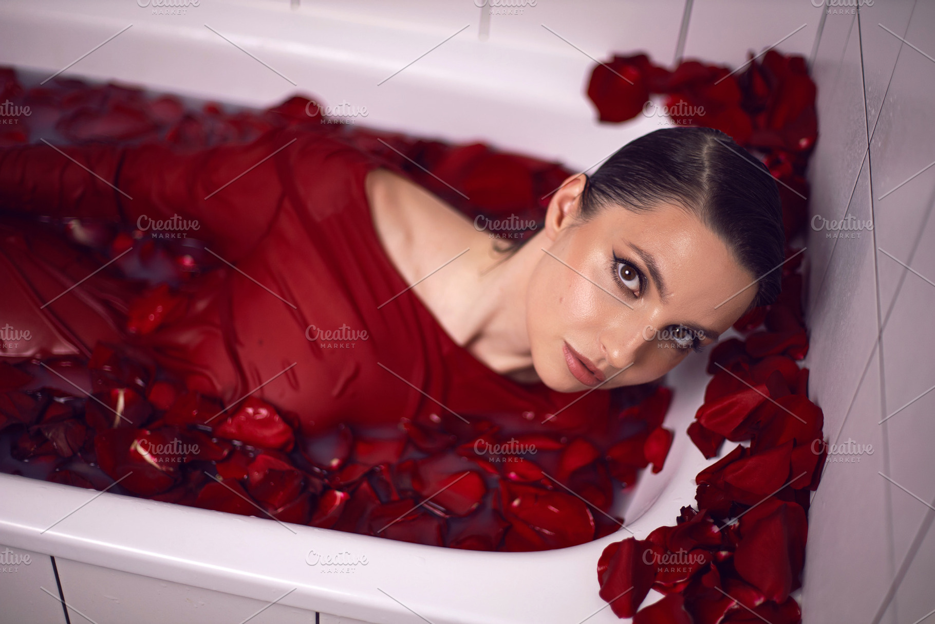 portrait of a beautiful sexy woman in a red dress lies in a white bathroom with, a Person Photo by SaulichPhoto