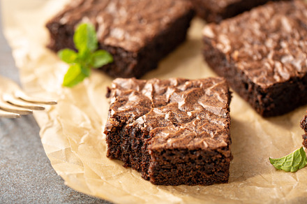 Freshly baked brownies on a parchment paper, a Food & Drink Photo by farwasser
