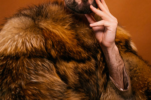 Man wearing fur coat, yellow beanie, and sunglasses, a Photo by karrastock