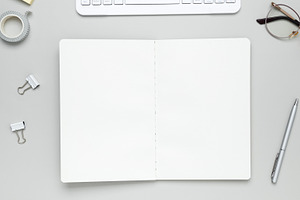Tidy workspace featuring stationery, keyboard, glasses, and notebook promoting