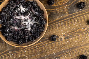 blackberries in a wooden bowl sprinkled with sugar , sour but ripe blackberries, a Photo by rsoollAI