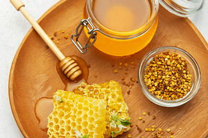 Jars and honeycombs resting on wooden tray, promoting natural sw, a Food & Drink Photo by Olena Rudo
