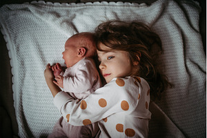 Young girl holding newborn sister, a Person Photo by HalfPoint