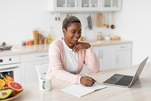 Smiling young pretty african american businesswoman working with laptop, a Person Photo by Prostock-Studio