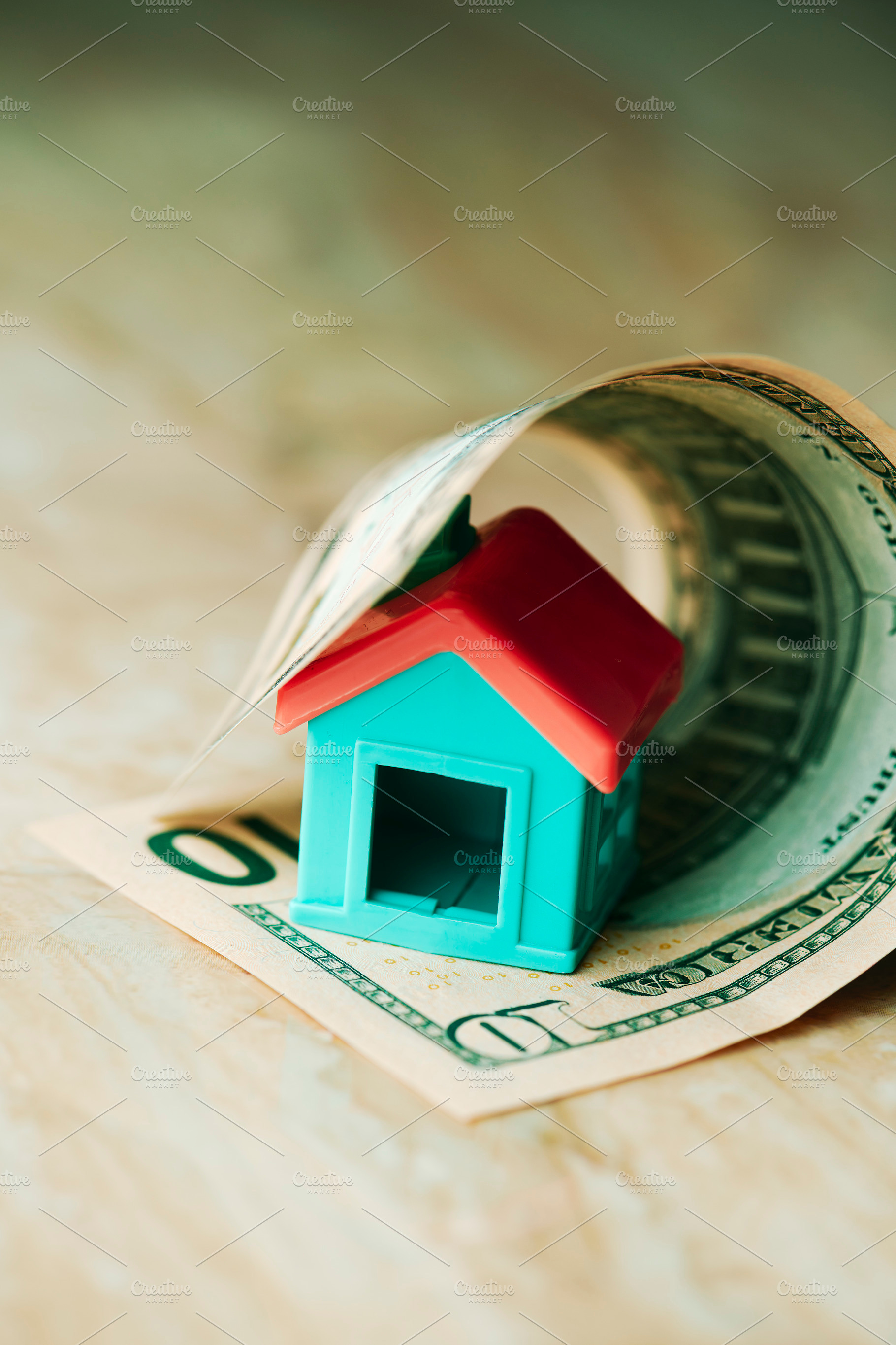 a small house emerging from a rolled dollar bill, a Photo by Nito
