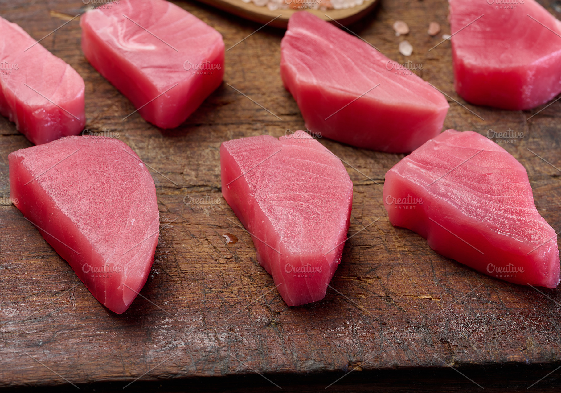 Raw tuna pieces on a brown wooden cutting board, a Food & Drink Photo by ndanko