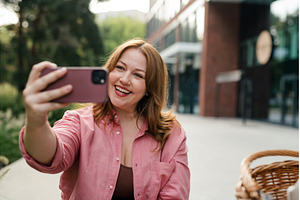 Curvy woman making videocall in park, a Business Photo by HalfPoint